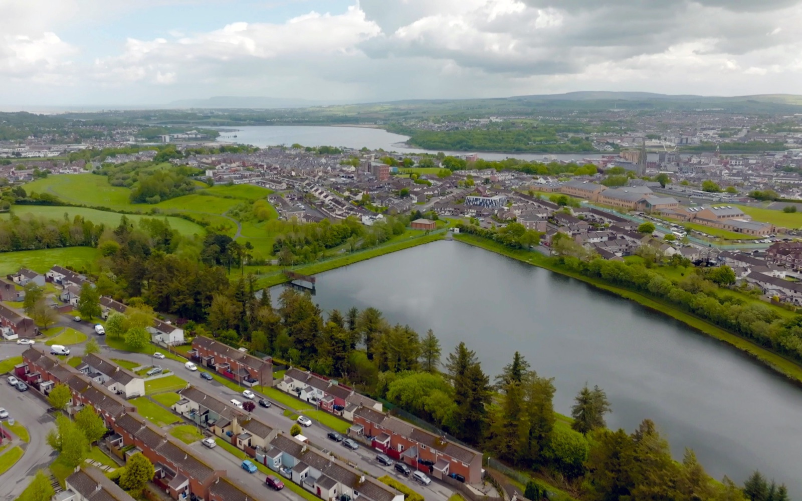 Aerial view over Creggan reservoir with the streets of Derry, the River Foyle and the hills beyond