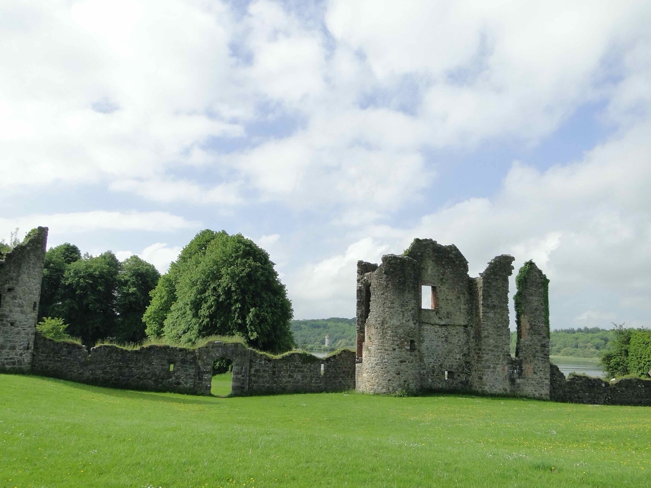 The Old Castle ruins at Crom rising from the grass above Upper Lough Erne, a broken stone tower and walls under a bright sky