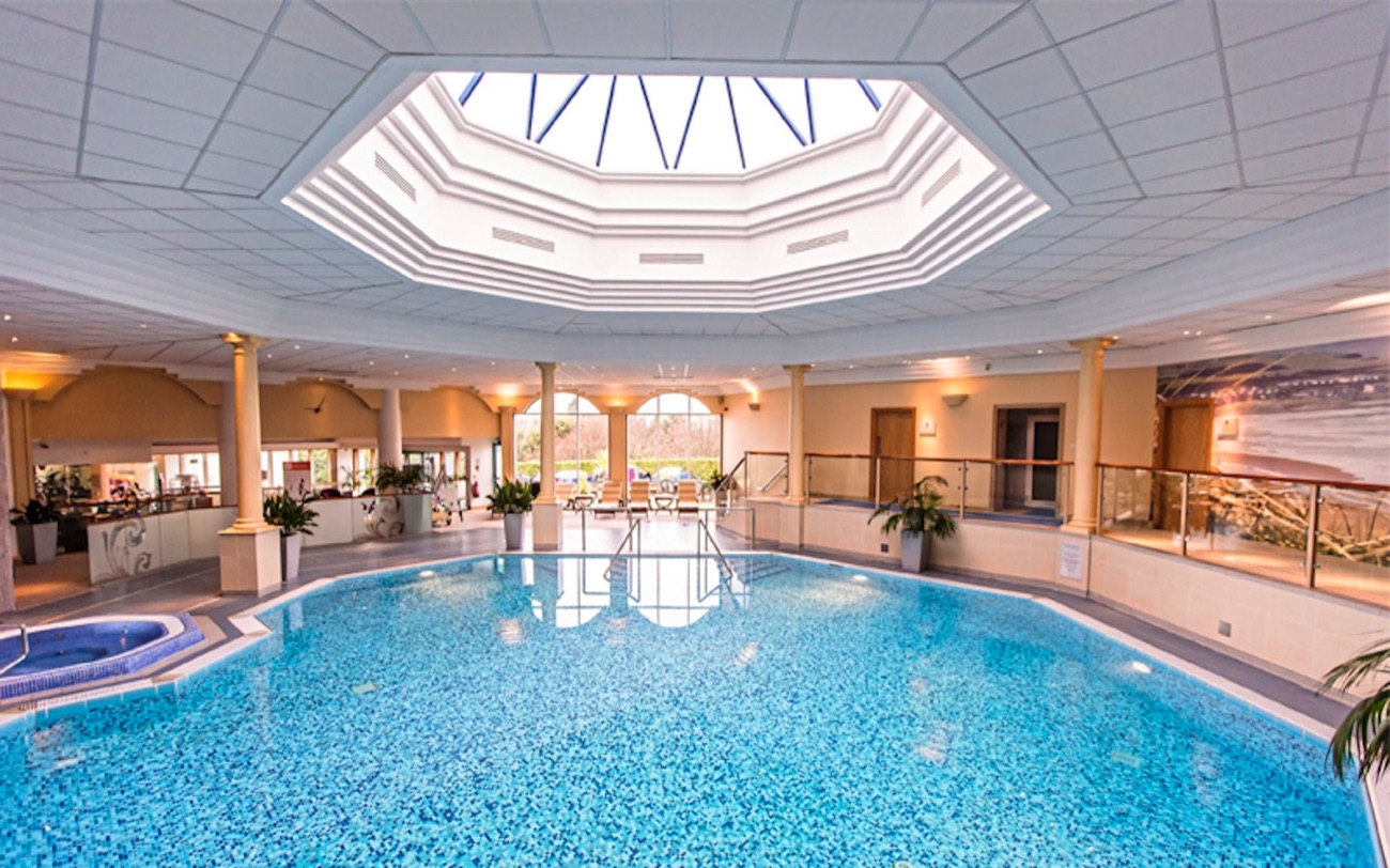 The pool under its octagonal skylight, with a corner jacuzzi and arched garden windows.