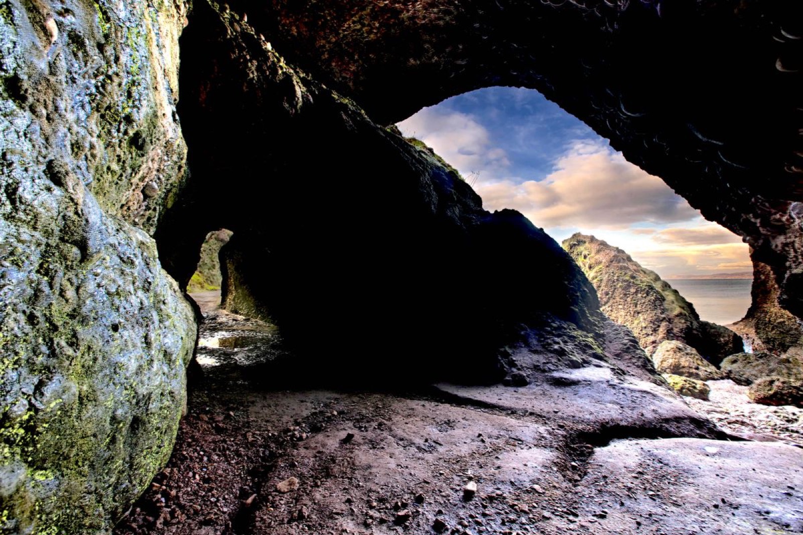 Looking out from inside a Cushendun sea cave through a rock arch to the sea and a glowing sky