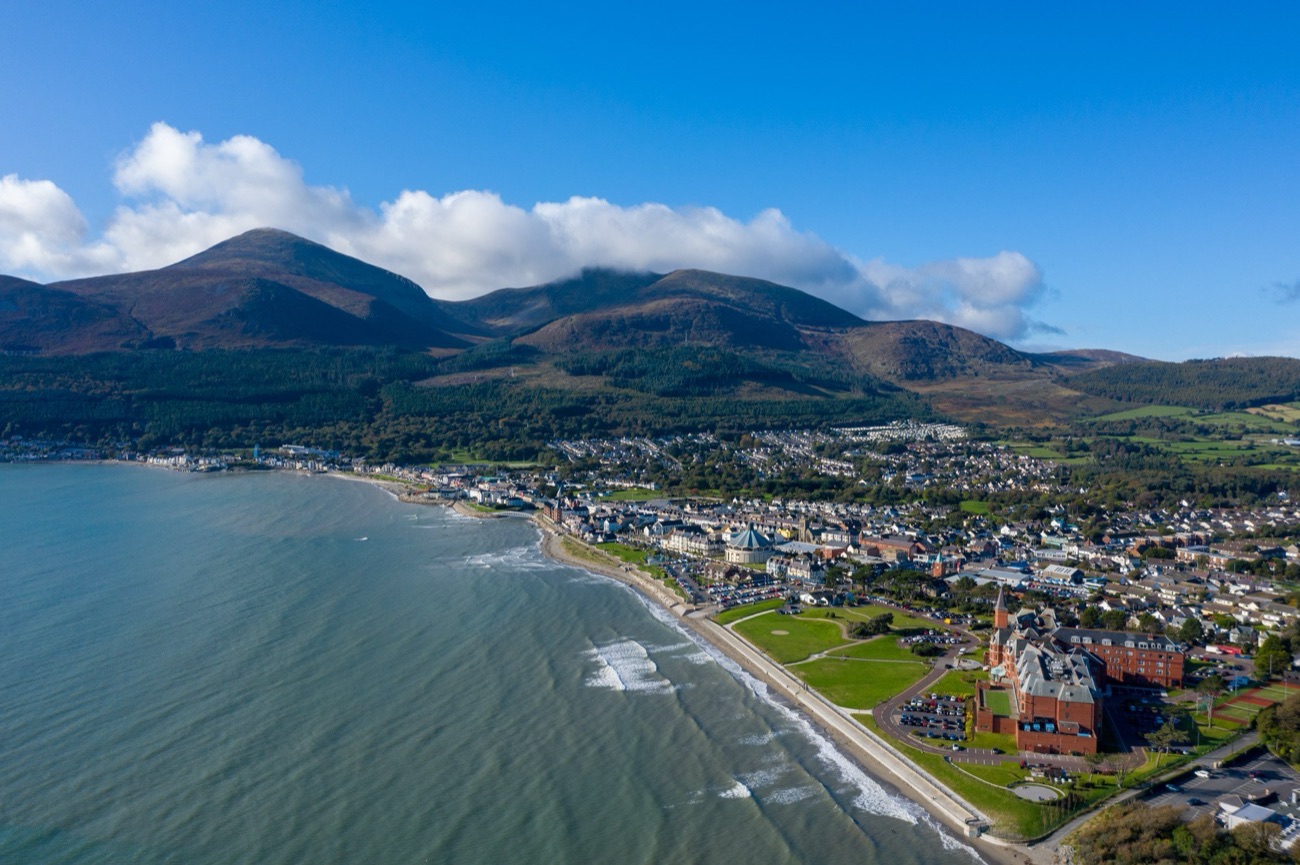 Aerial view of Newcastle's seafront and long sandy beach with the Mourne Mountains rising directly behind the town
