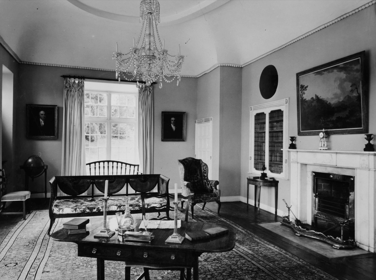 The elegant drawing room inside Derrymore House, with a crystal chandelier, marble fireplace and family portraits