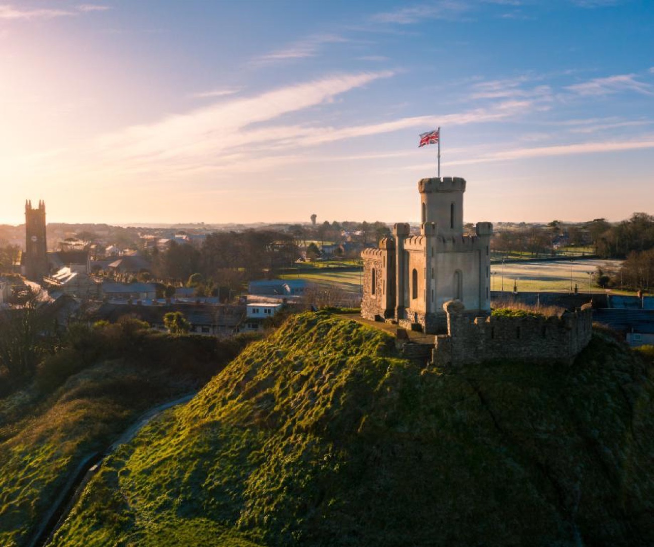 The motte and gunpowder store above Donaghadee at sunset with the town and church below