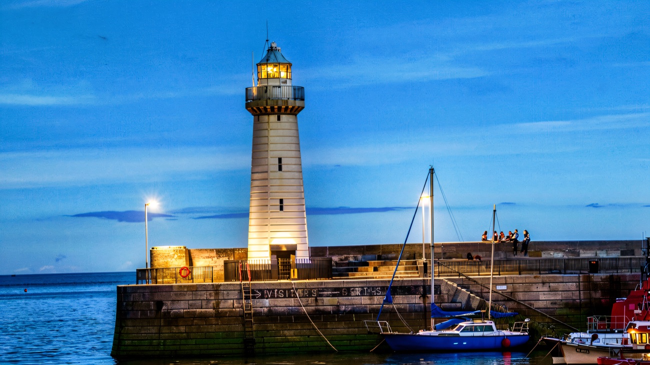 The lighthouse and harbour wall above brilliant blue water