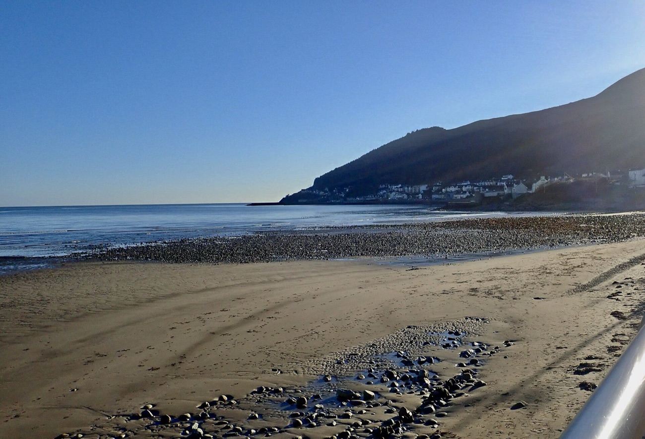 Newcastle beach and the Mourne Mountains on a sunny day beside Donard Park