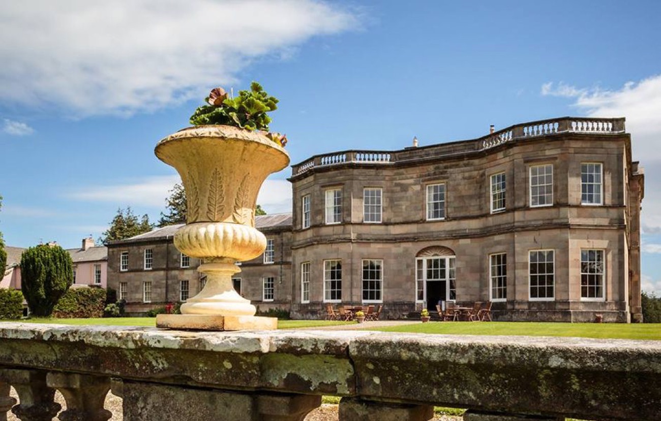 A carved stone urn on the terrace balustrade with the sunlit mansion behind