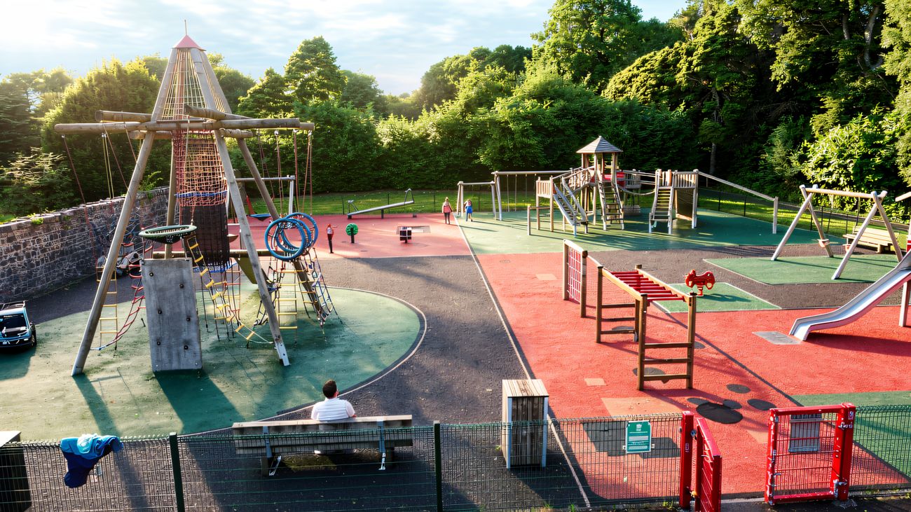 The Drum Manor play park from above showing the rope pyramid, swings and red and green surfacing