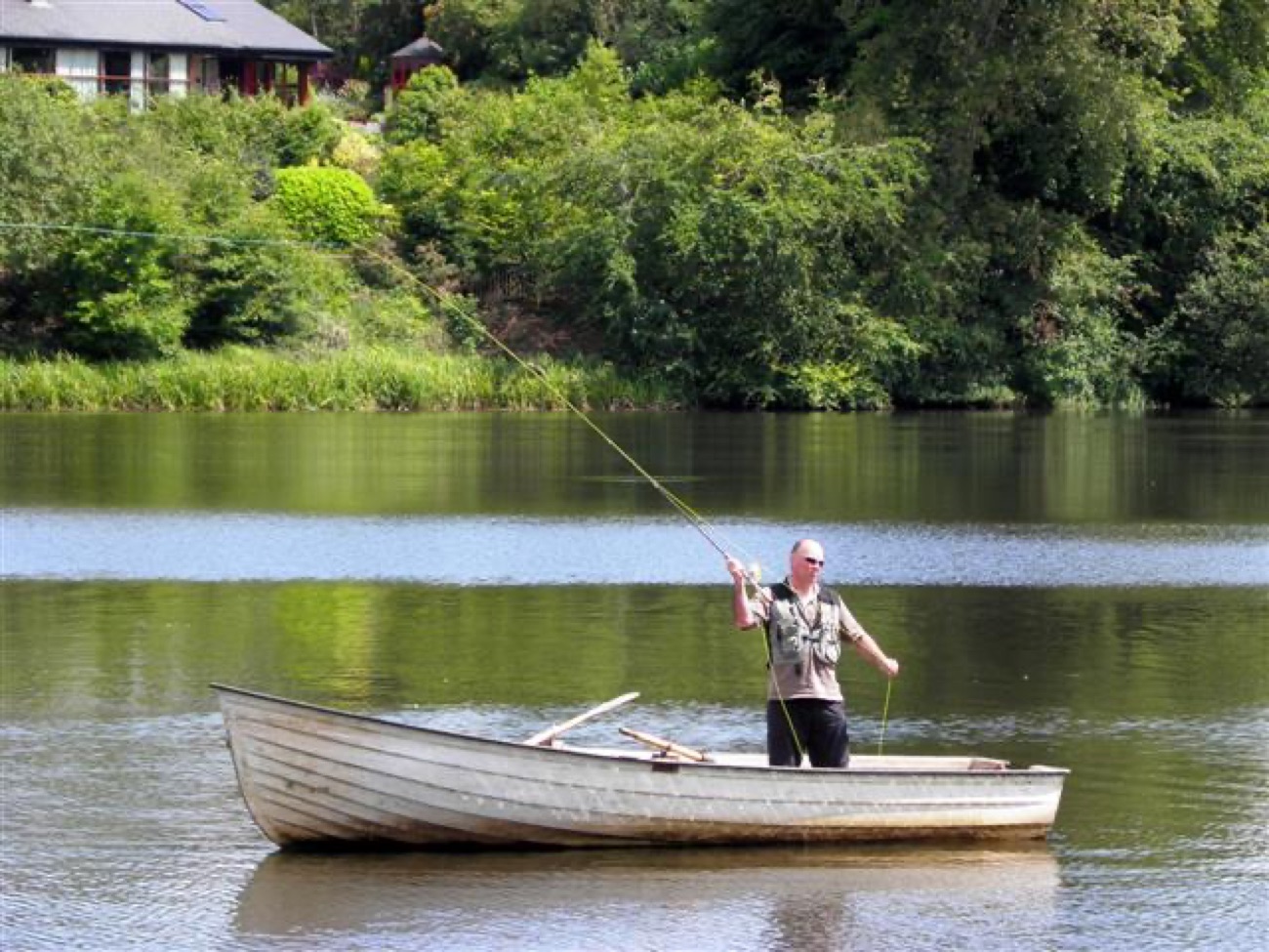 An angler fly-fishing from a boat on Dungannon Park lake