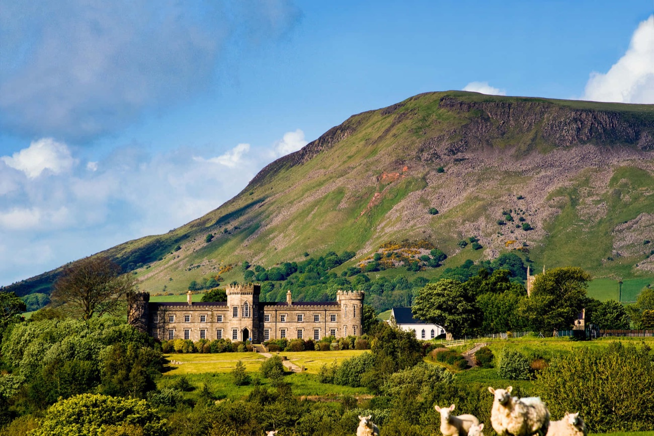 Dungiven Castle set in green fields below the slope of Benbradagh mountain, with sheep grazing