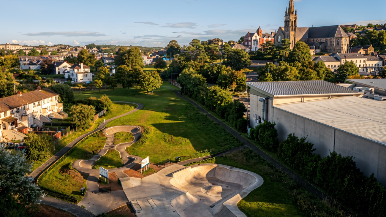 Aerial view of the concrete bowl and winding pump track with Downpatrick behind