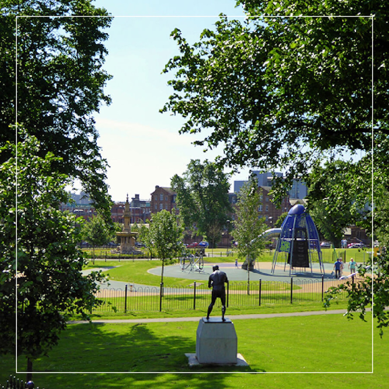 The open green at Dunville Park with the play area and the Belfast skyline behind