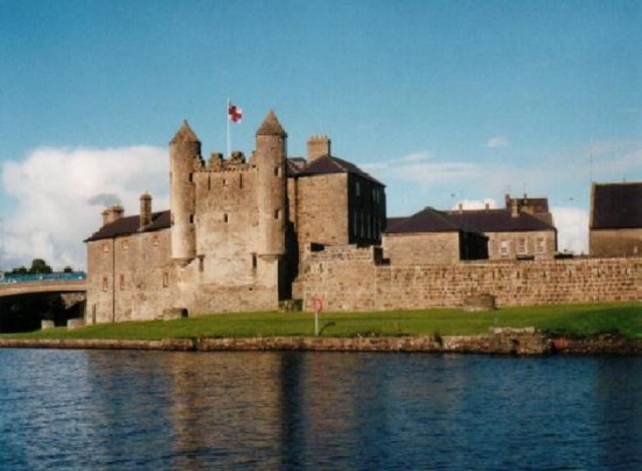 The keep and curtain walls of Enniskillen Castle seen from the water, its turreted tower rising above the barracks buildings