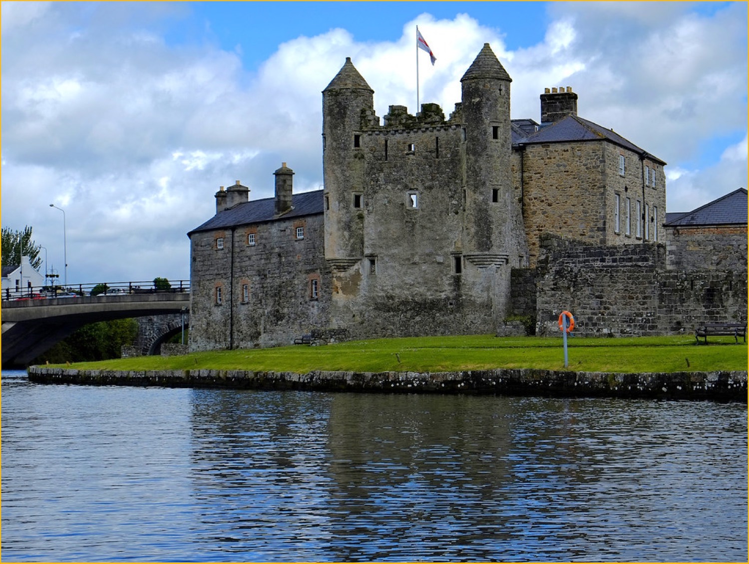 Enniskillen Castle across the River Erne — the twin-turreted Watergate and grey stone keep, with a flag flying above