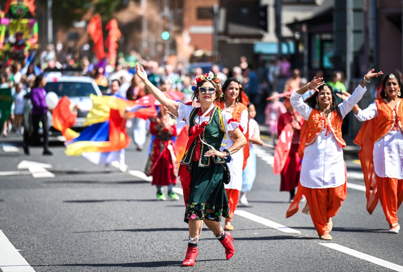 Colourful carnival dancers and flags parading up the Falls Road as crowds line the street at Féile