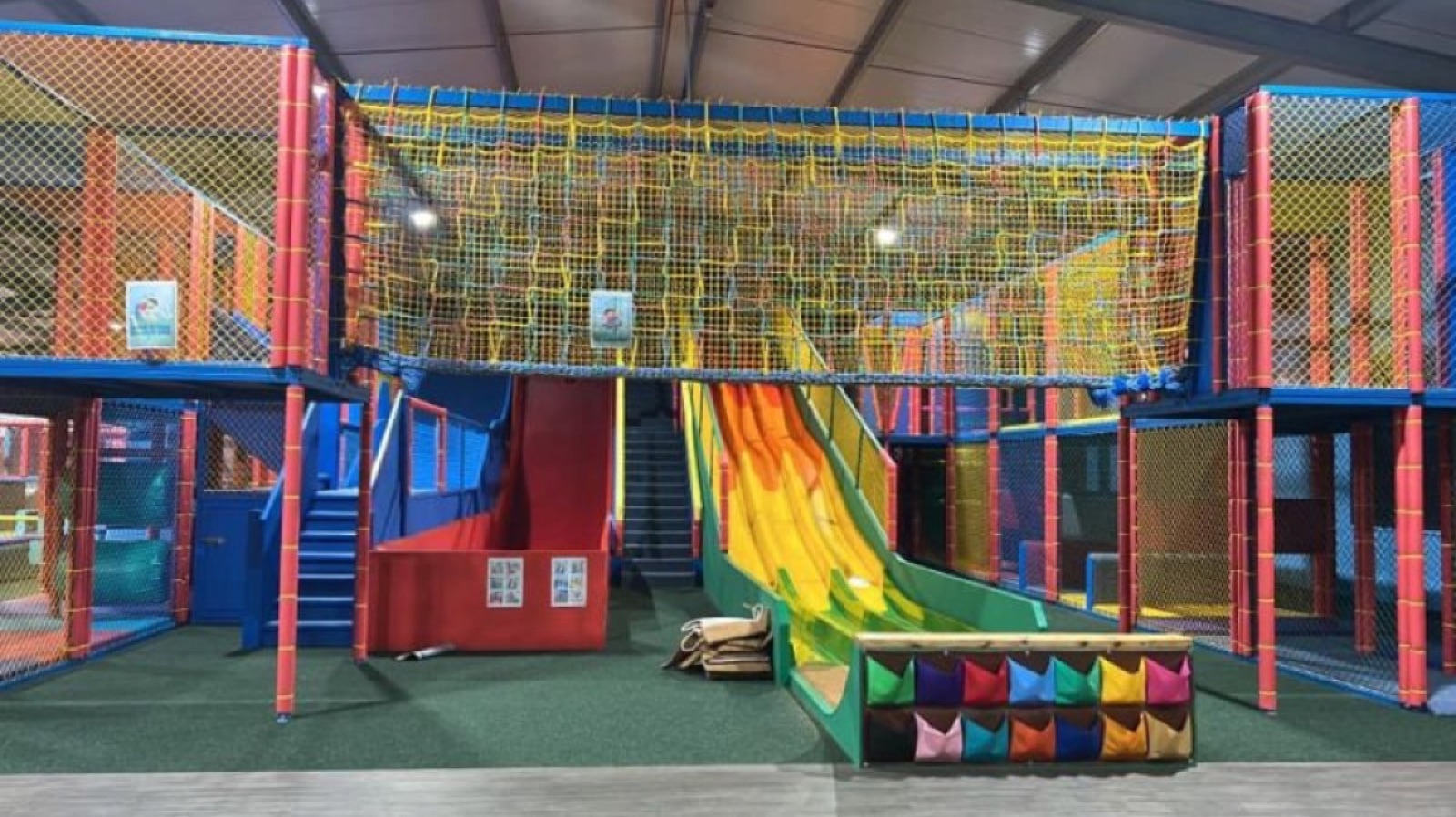 The colourful indoor soft-play frame with a yellow tube slide in the play barn at Fermanagh Fun Farm