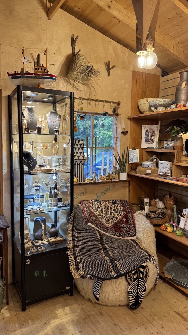 A glass cabinet of jewellery and gifts beside a sheepskin-covered stool at Fodder