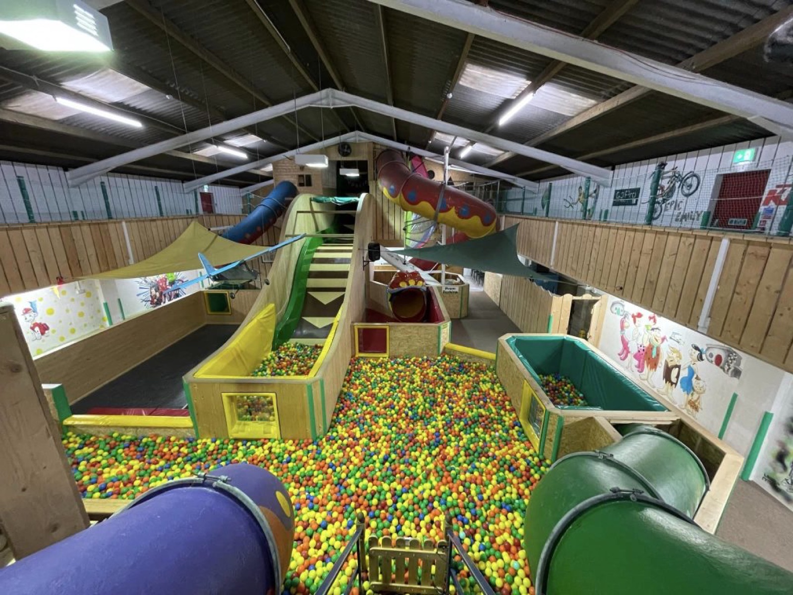 The huge indoor soft-play barn at Fort Evergreen with dragon slides, a big ball pool and tube slides under a timber roof