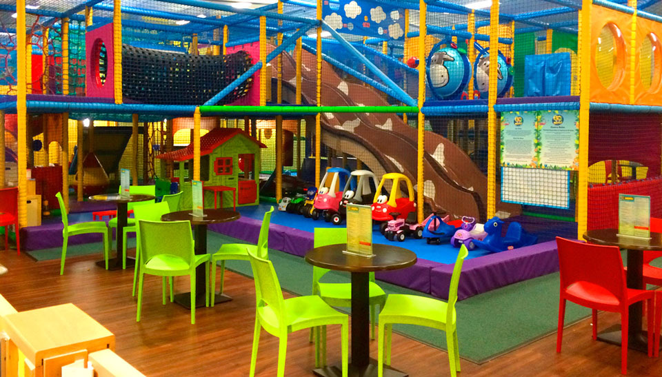 The jungle-themed multi-level soft play frame at Funky Monkeys Dundonald, with slides, little coupe cars and café tables in front