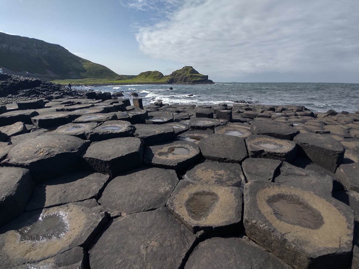 Hexagonal basalt columns with the green pinnacle behind