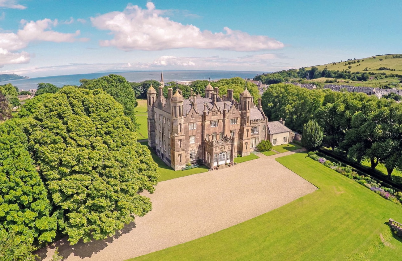 Glenarm Castle in its wooded estate with the Antrim coast and sea behind
