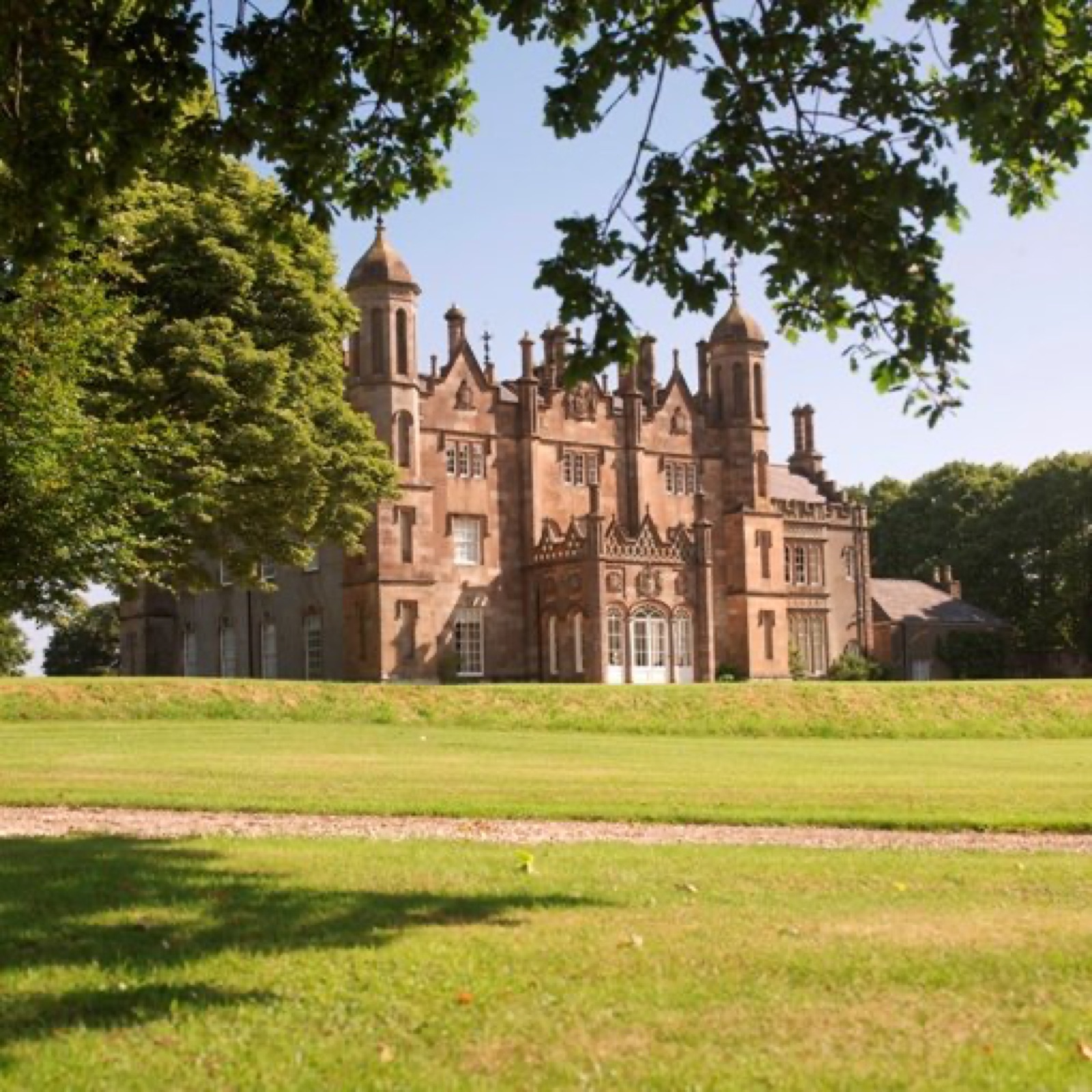 The turrets of Glenarm Castle framed by a tree in golden evening light
