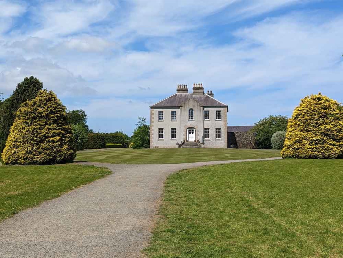 Gracehill House, a grey-stone Georgian house at the end of a gravel drive under a blue sky