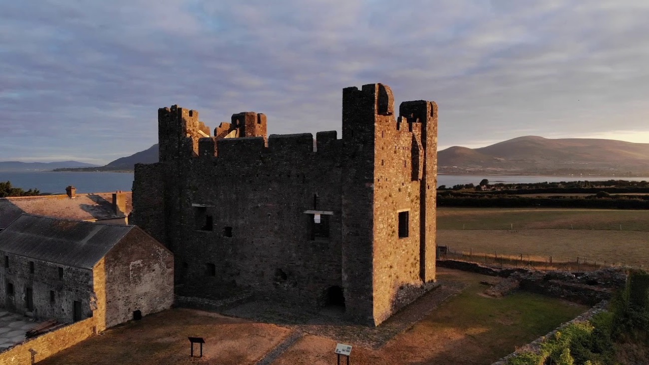 The great keep of Greencastle Royal Castle at golden hour, with Carlingford Lough and the Cooley mountains behind