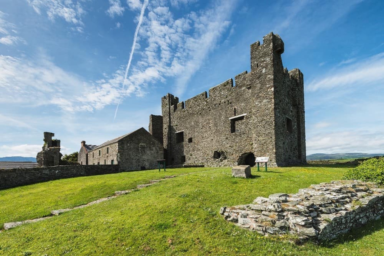 Greencastle's keep with its corner tower, curtain wall and grass sward under a blue sky