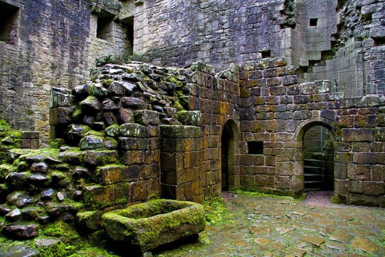 Inside the ruined keep of Greencastle — mossy stone walls, arched doorways and a flagstone floor