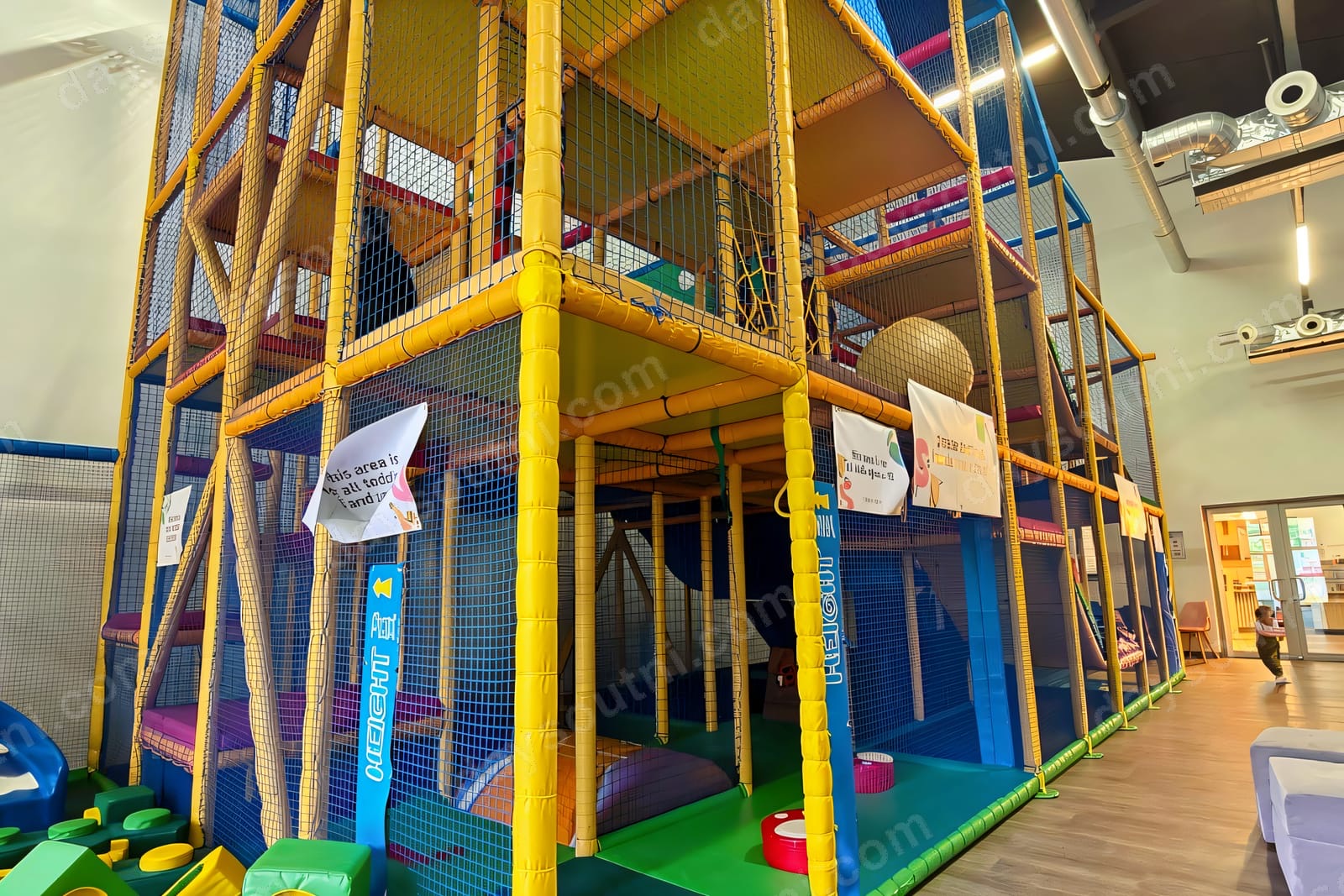 The multi-level yellow-and-blue soft play frame at Happy Days in Lisburn, with netting and climbing sections