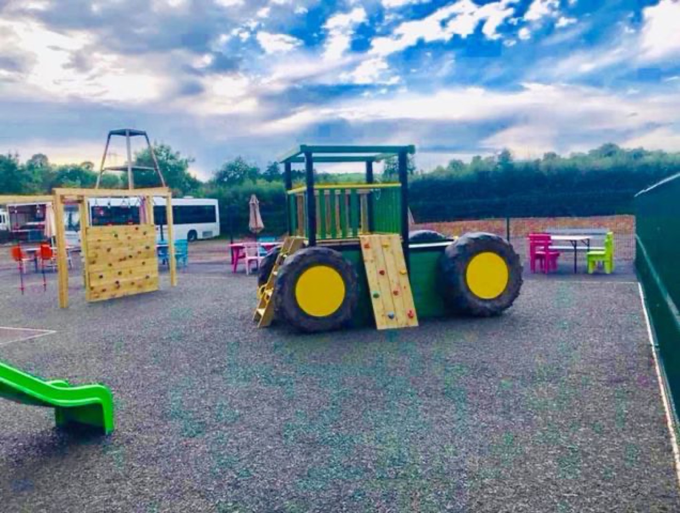 The outdoor play area at Happy Dayz near Ballygawley, with a green tractor climbing structure, a slide and picnic seating on a soft safety surface