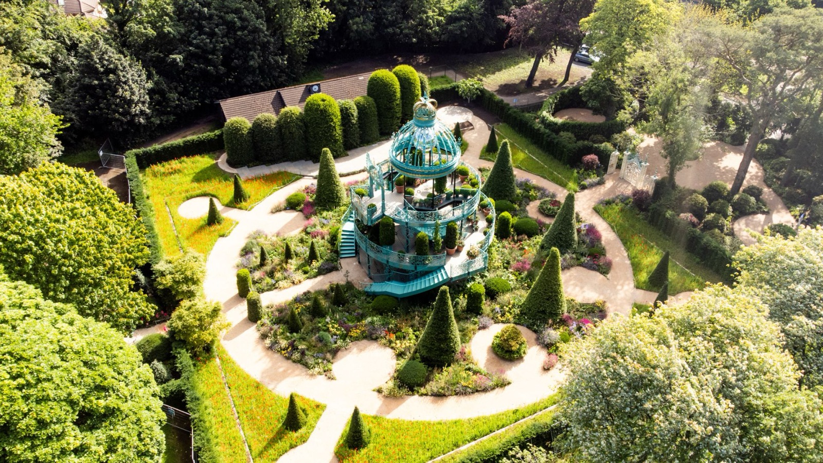 Aerial view of the Coronation Garden at Hazelbank Park — a tiered turquoise ironwork pavilion surrounded by topiary cones and spiral paths