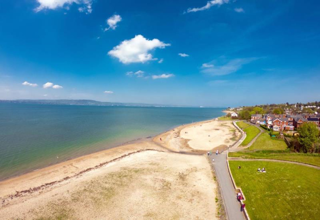 Aerial view along the Holywood shoreline with the beach, the green strip of parkland and the blue water of Belfast Lough