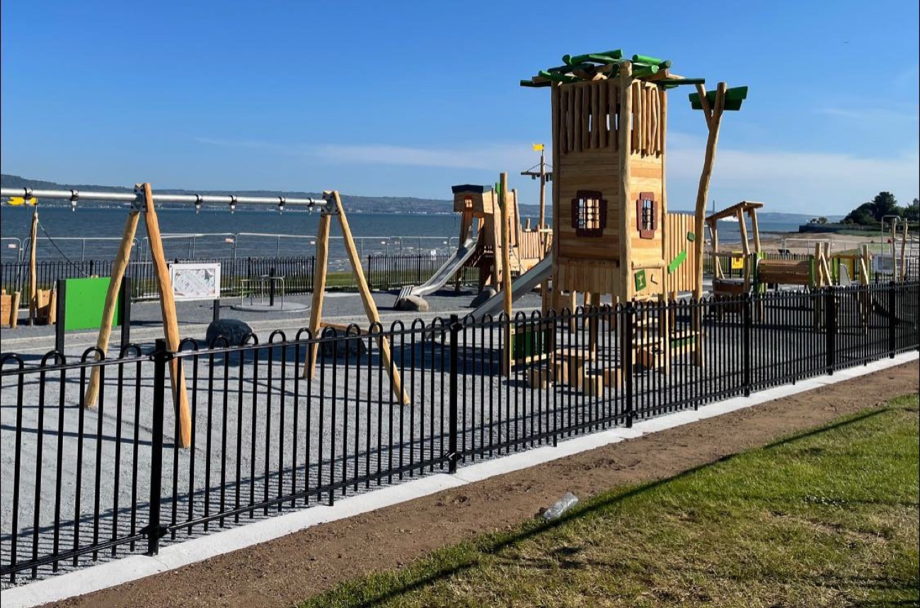 A wooden climbing tower in the play park at the Holywood seafront with the lough behind