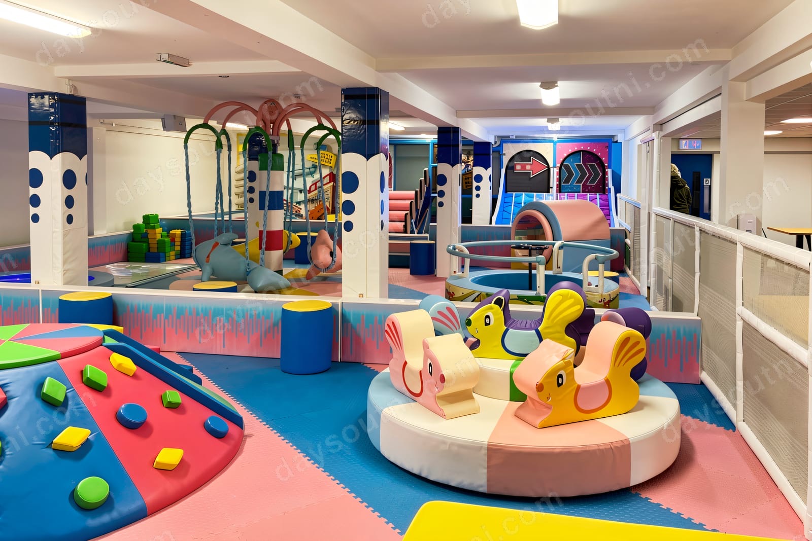 The bright pastel-coloured interior of Honeybees Playtown in Ballymena, with soft climbing shapes, a merry-go-round and a role-play area