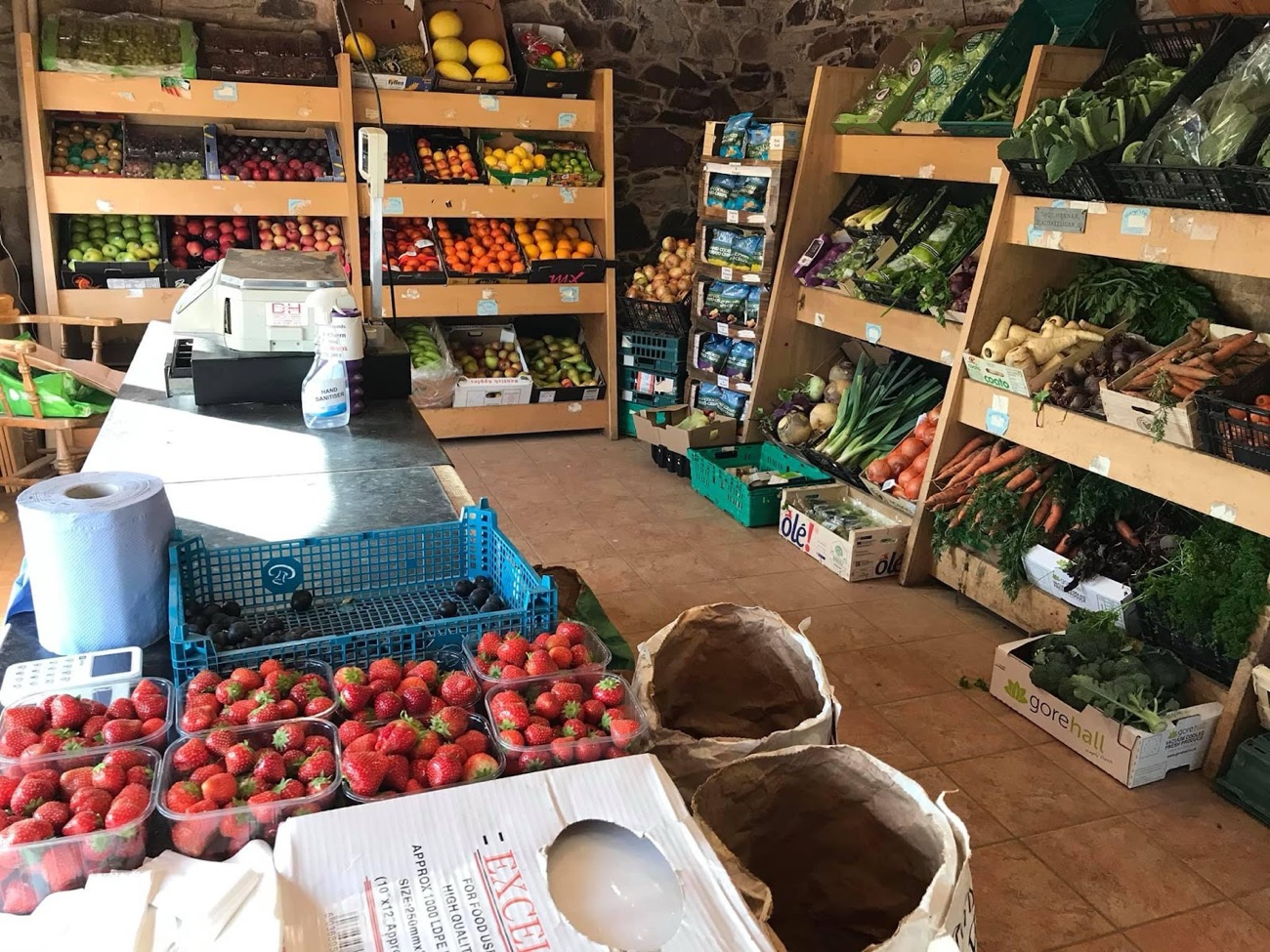 Inside Horner's: wooden shelves of vegetables and trays of strawberries by the till