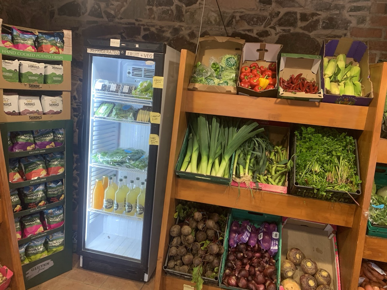 Shelves of leeks, beetroot, onions and greens beside the drinks fridge