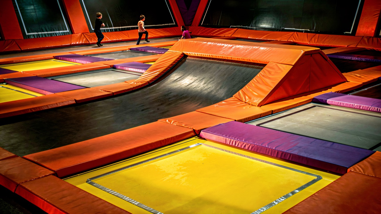 A wider view across the trampoline arena with angled orange ramps and springy walls