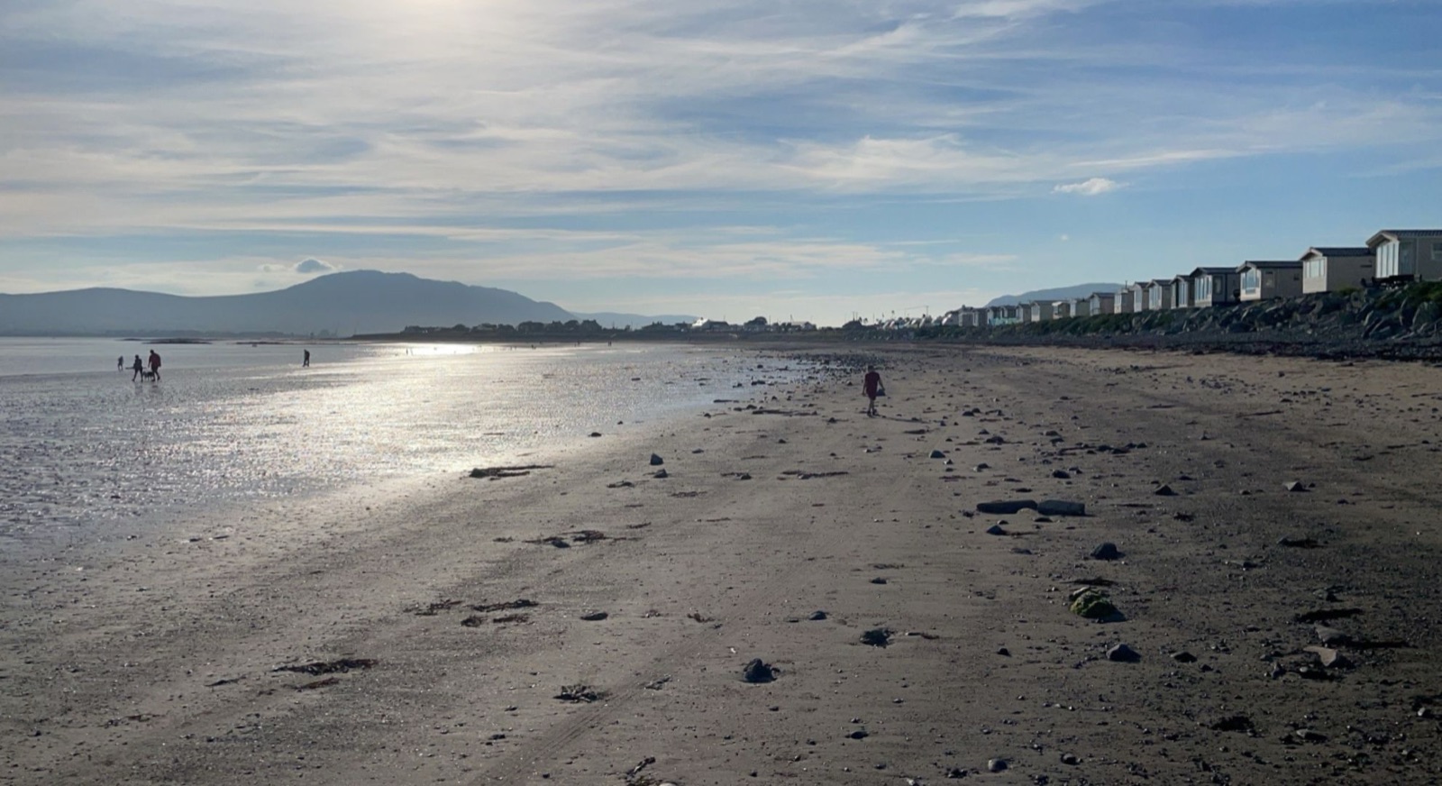 The long sandy beach at Cranfield, Kilkeel, with wet sand glinting in the sun and the Mourne Mountains rising across Carlingford Lough