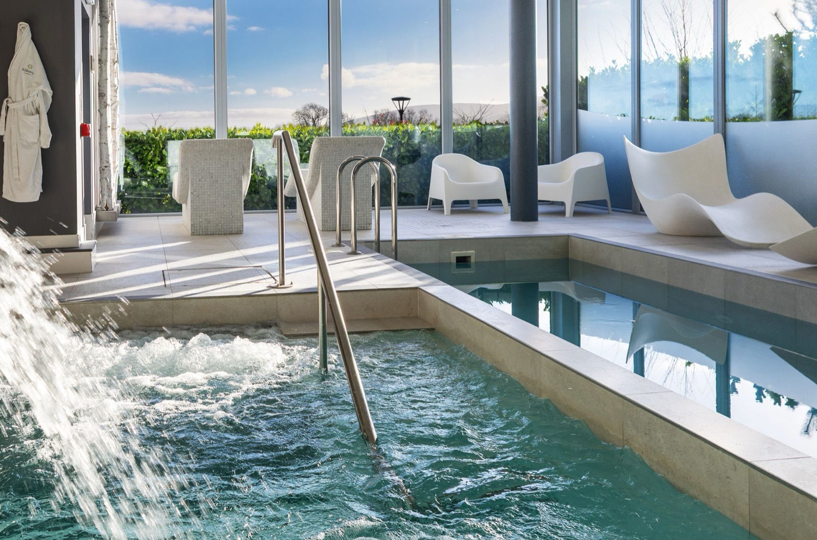 The mountain-view hydro pool at Killeavy Castle spa, water bubbling under floor-to-ceiling glass onto the walled garden.