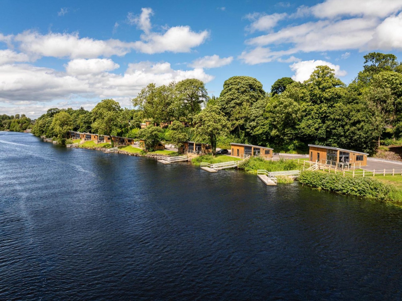 A row of timber self-catering chalets set among trees right on the lakeshore at Killyhevlin