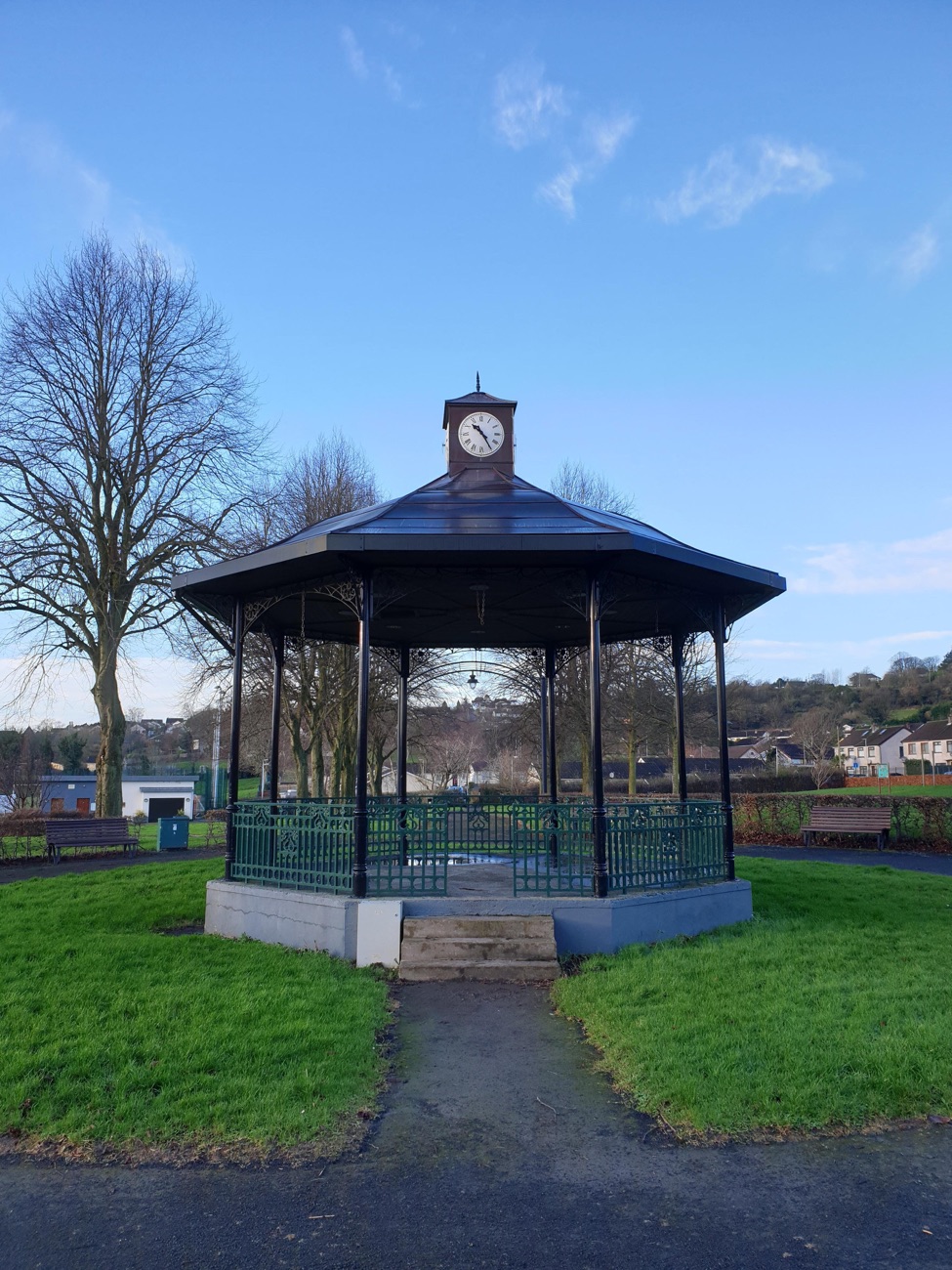 The bandstand at Larne Town Park with its dark roof and clock, ringed by bare trees