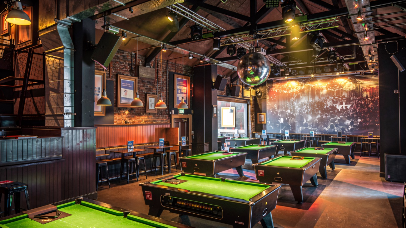 The pool room upstairs, with rows of tables under low lights
