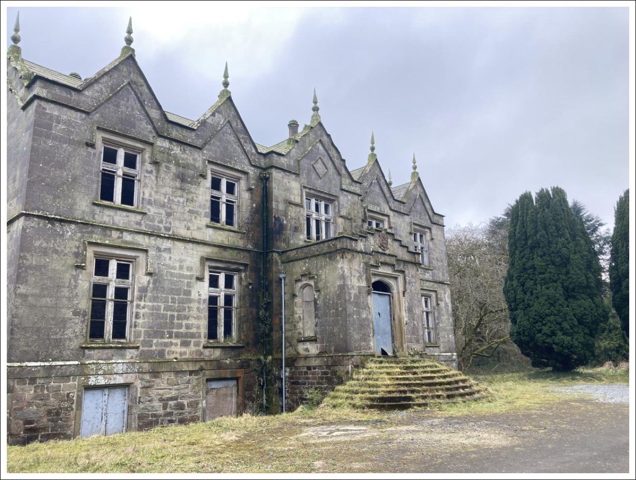 The gabled Tudor-Gothic elevation of Learmount Castle with pointed finials and mossy stone steps