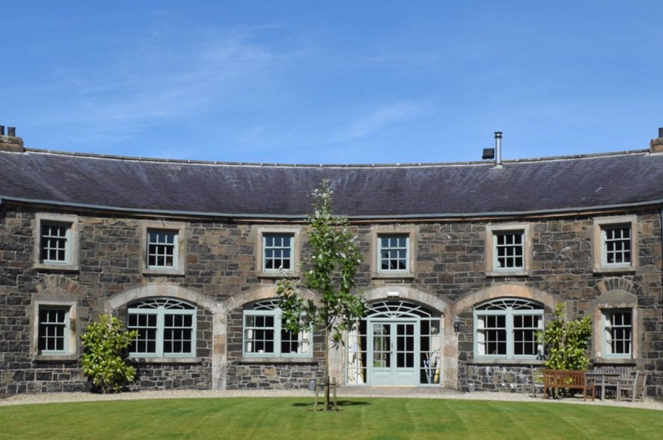The restored curved coach-house courtyard in stone, with tall arched windows
