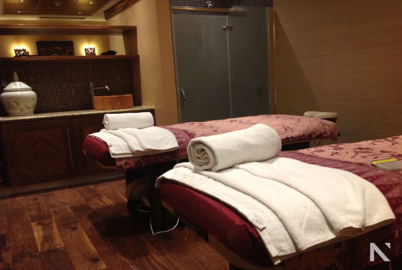A warm-lit treatment room with two therapy beds and Thai décor.