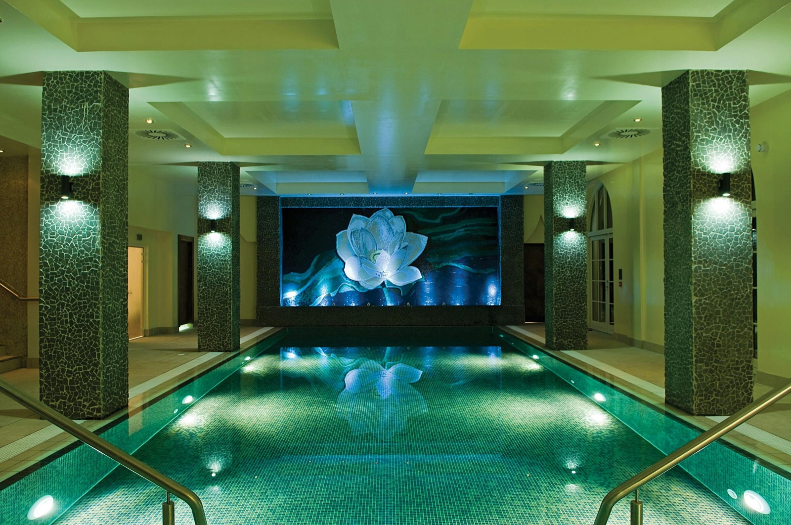 The Thai Spa infinity pool, lit soft green beneath a lotus mosaic.