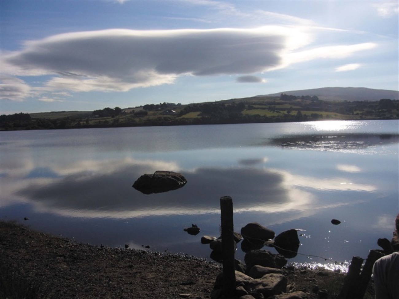 Cloud reflections and shore rocks at the edge of Lough Fea