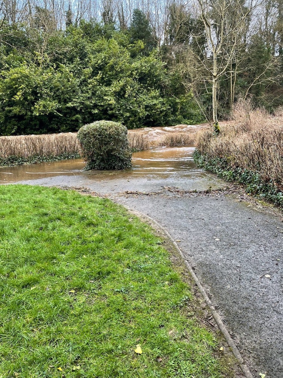 The riverside path at Lover's Retreat curving past clipped shrubs beside the water