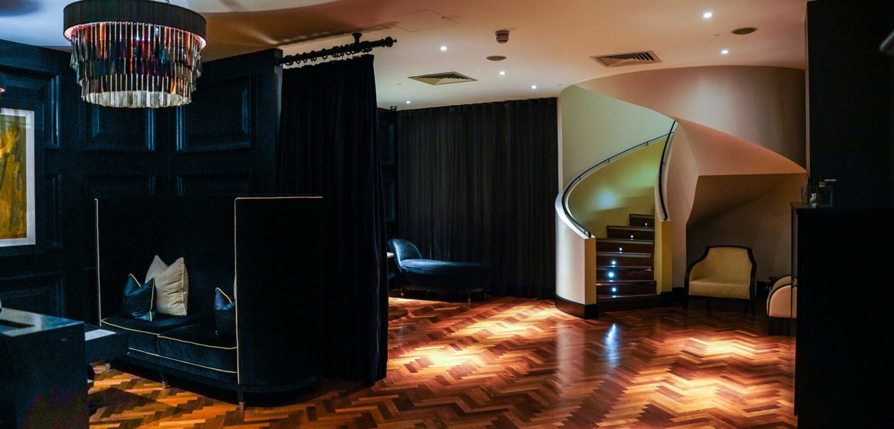 The spa lounge, with its dark panelling, chandelier and a curved staircase.